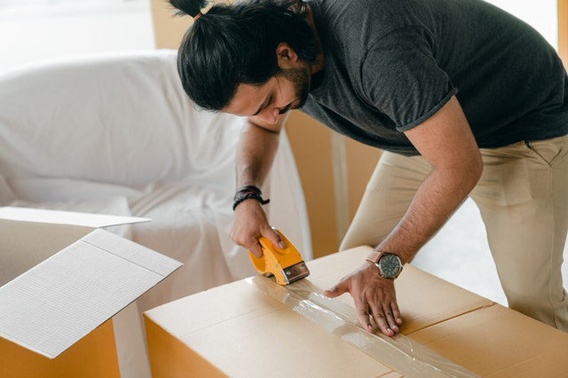 Man sealing a cardboard box with packing tape